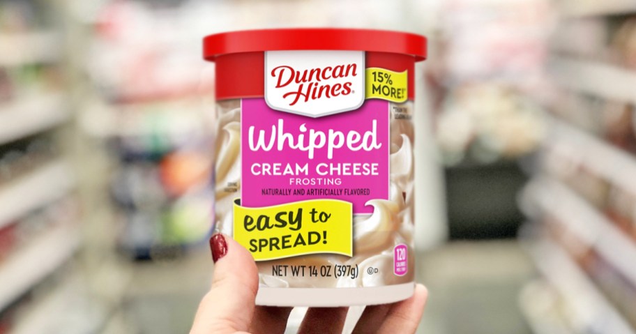 hand holding a can of Duncan Hines Whipped Cream Cheese Frosting in store