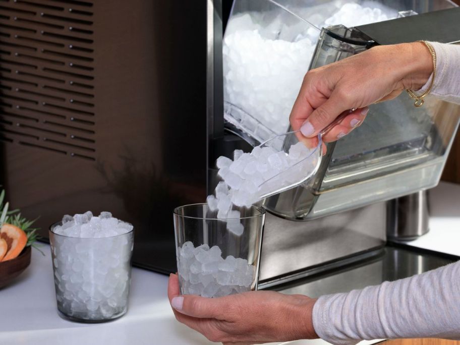 Woman scooping nugget ice from a GE Profile Nugget Ice Maker into a glass 