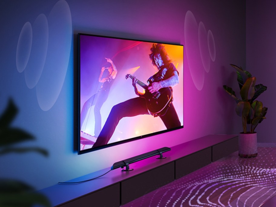 tv on wall with a light bar underneath, colorful lights around it