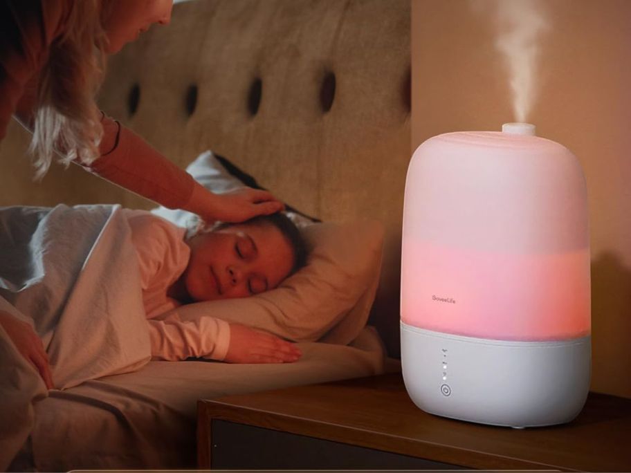 A girl laying in a bed near a Govee Life Smart Humidifier Night Light