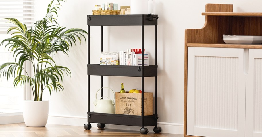 a slim black storage cart with kitchen items on it in a kitchen