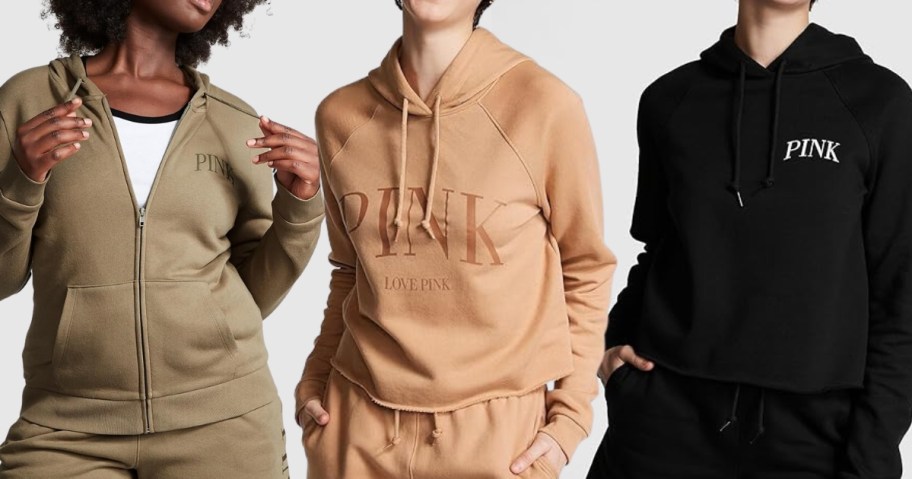 3 women wearing Victoria's Secret PINK hoodies, 1 in an olive zip up style, 1 in a peach golden crop hoodie and 1 in a black crop hoodie