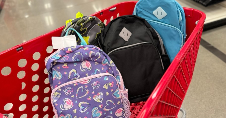 kid's backpacks in various colors and patterns in a Target shopping cart