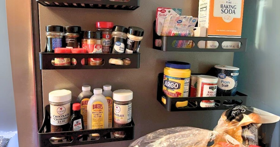 side of a fridge with 4 black magnetic spice racks filled with kitchen items