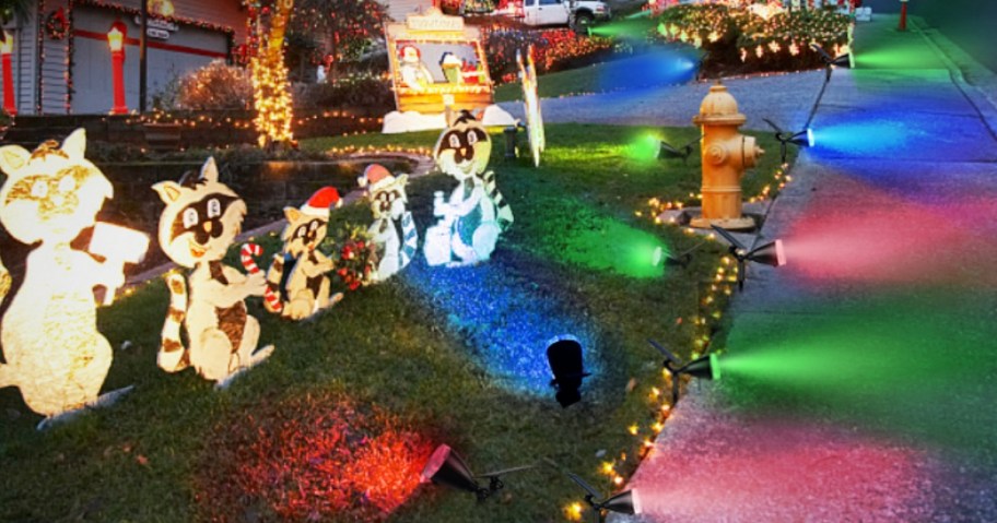 yard with Christmas decor and colorful solar powered spotlights shining on them