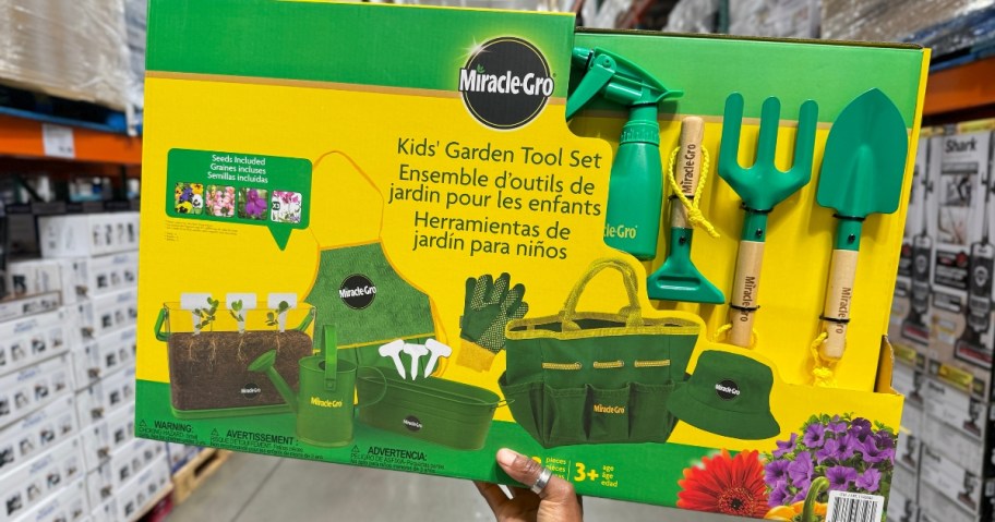 hand holding a green and yellow box with a Miracle Gro Kids’ Garden Tool Set in it