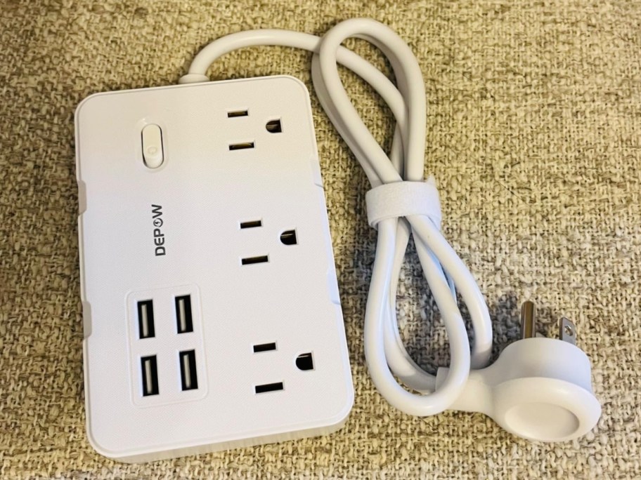 white power strip charging station laying on carpet, flat cord showing