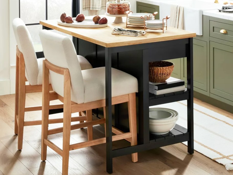 black kitchen island with wood top with two dining chairs seated at it