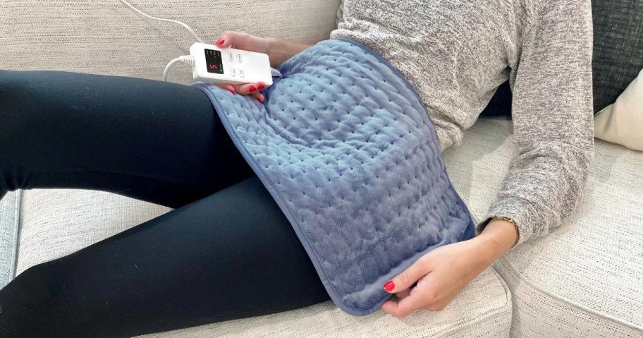 woman sitting on couch with heating pad