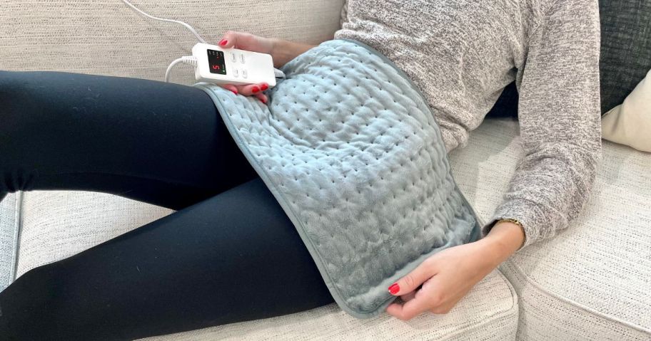 woman using Heating Pad from Amazon on a sofa