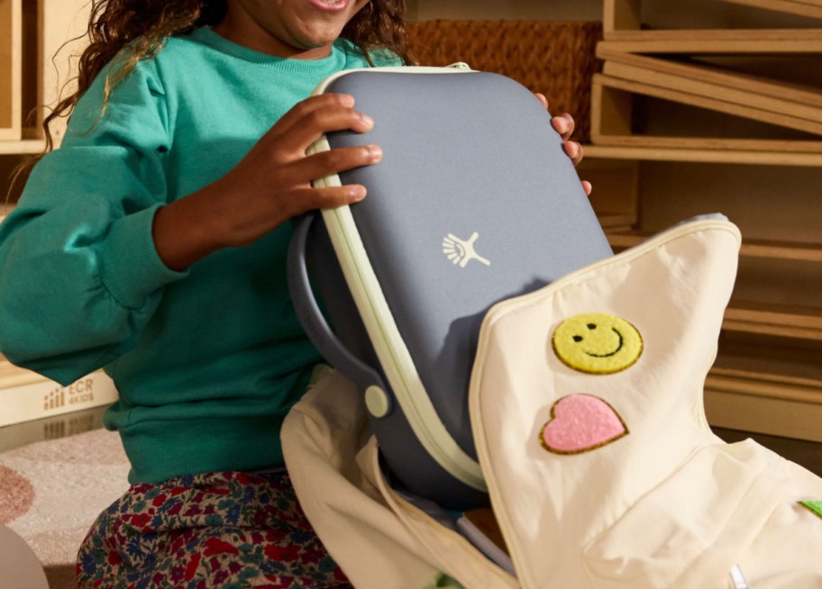 girl taking hydro flask lunch box out of bookbag with felt patches