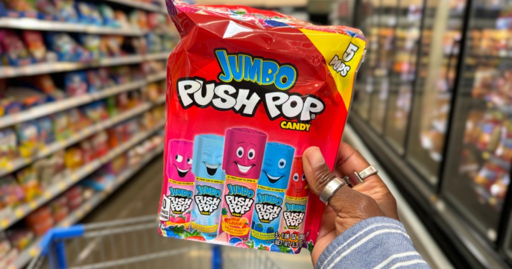 person holding up jumbo push pop candy inside walmart store