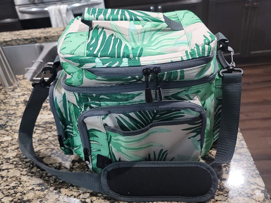 green tropical leaf print mini cooler / lunch bag with carry strap sitting on a kitchen counter