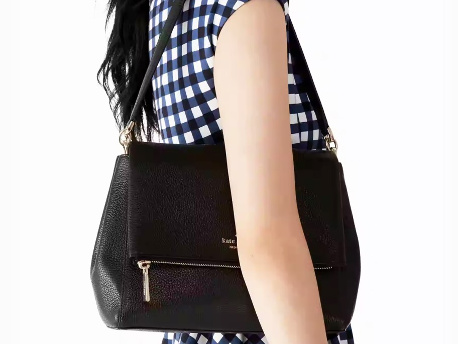 woman in a navy blue and white gingham dress with black shoulder bag