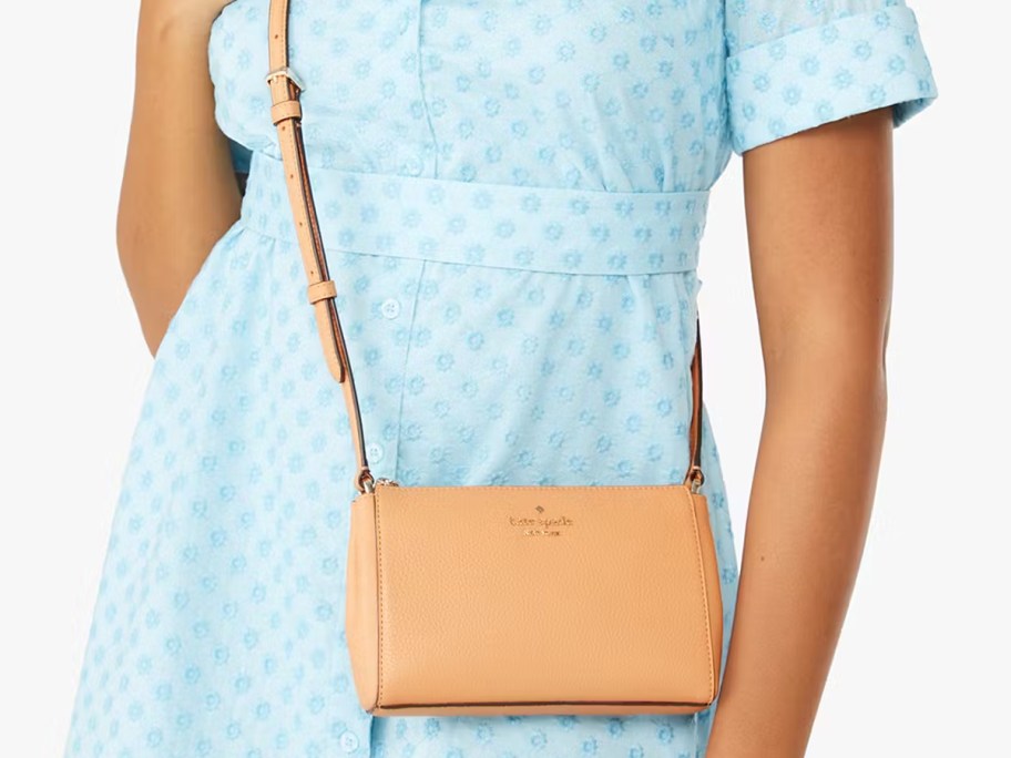 woman in a blue dress with a tan crossbody bag
