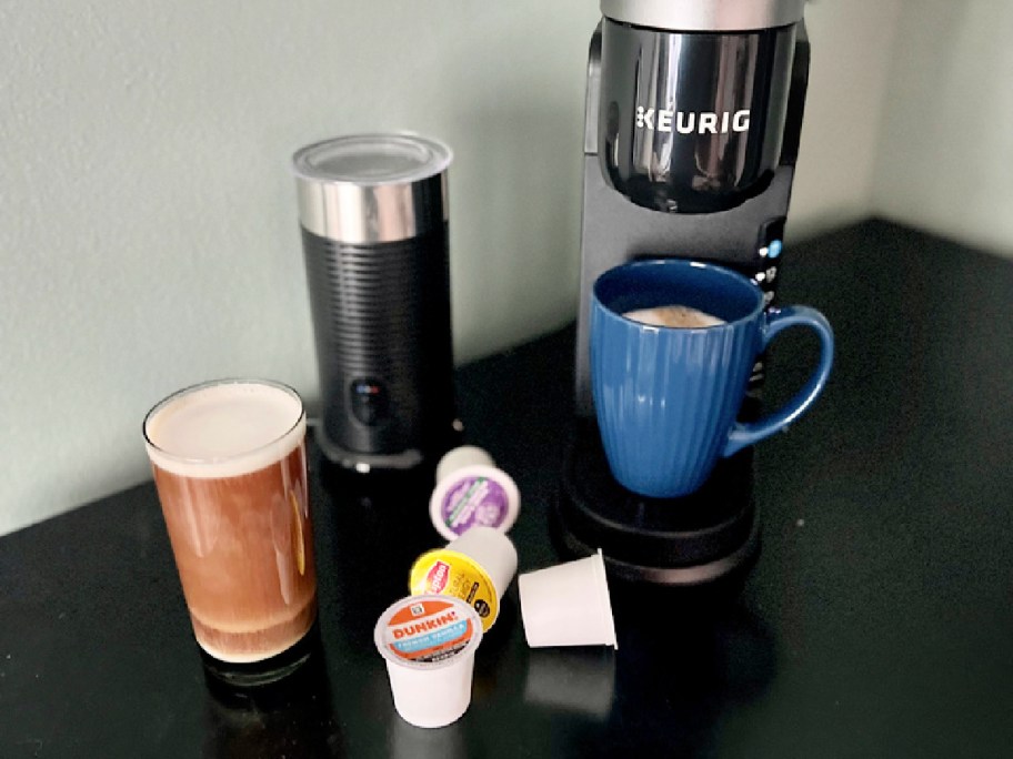 blue coffee mug on a black keurig behind k-cups