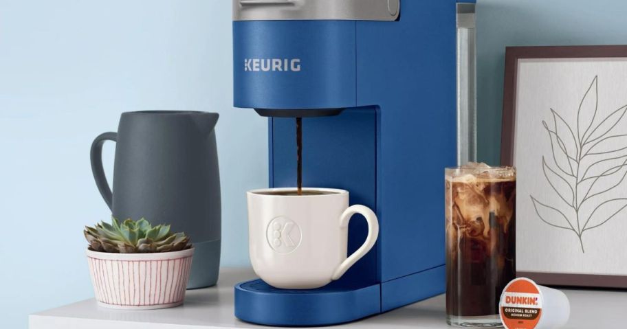 A blue Keurig K-Slim Coffee Maker next to a cup of Iced coffee