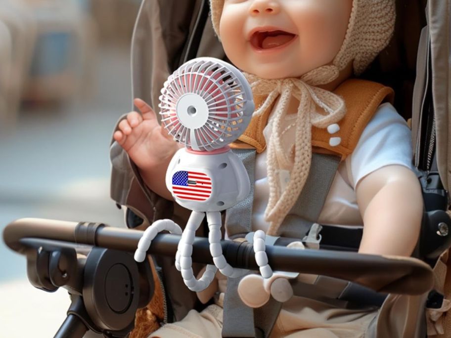 A baby with a small fan attached to their stroller