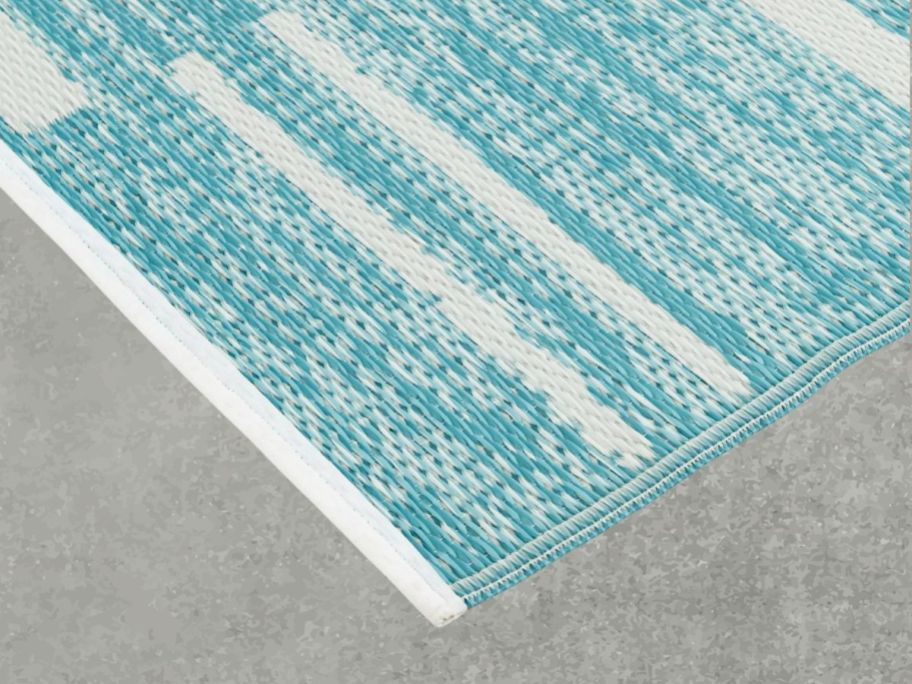 Mainstays 5' x 7' Teal Geo Stripe Outdoor Rug on cement