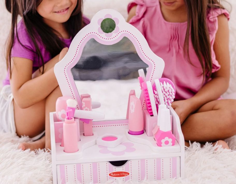 2 little girls playing with a melissa & doug vanity set