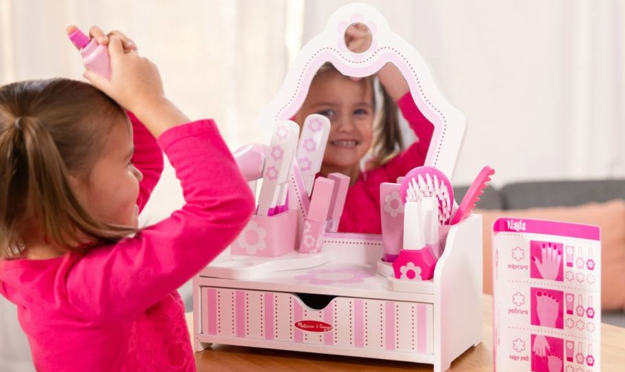 a little girl playing with a melissa & doug vanity set
