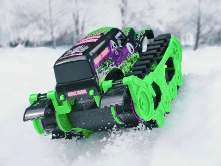 a green monster jam tank rolling down a snow covered hill