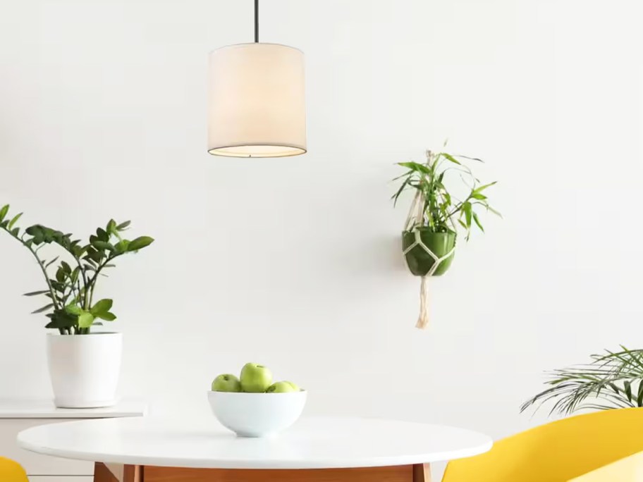 small pendant light fixture with white shade hanging over table