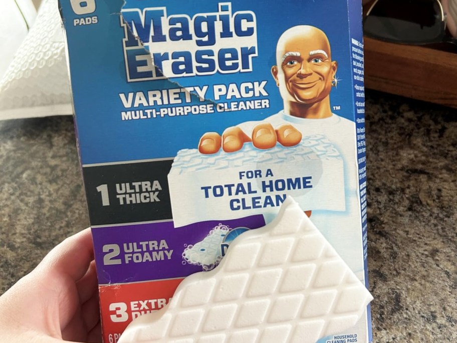 hand holding a box of Mr. Clean Magic Eraser Variety 6-Pack with eraser in front of the box