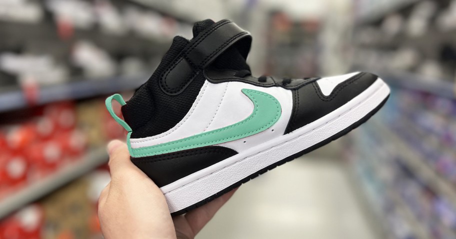 hand holding up a black, white, and mint green nike sneaker