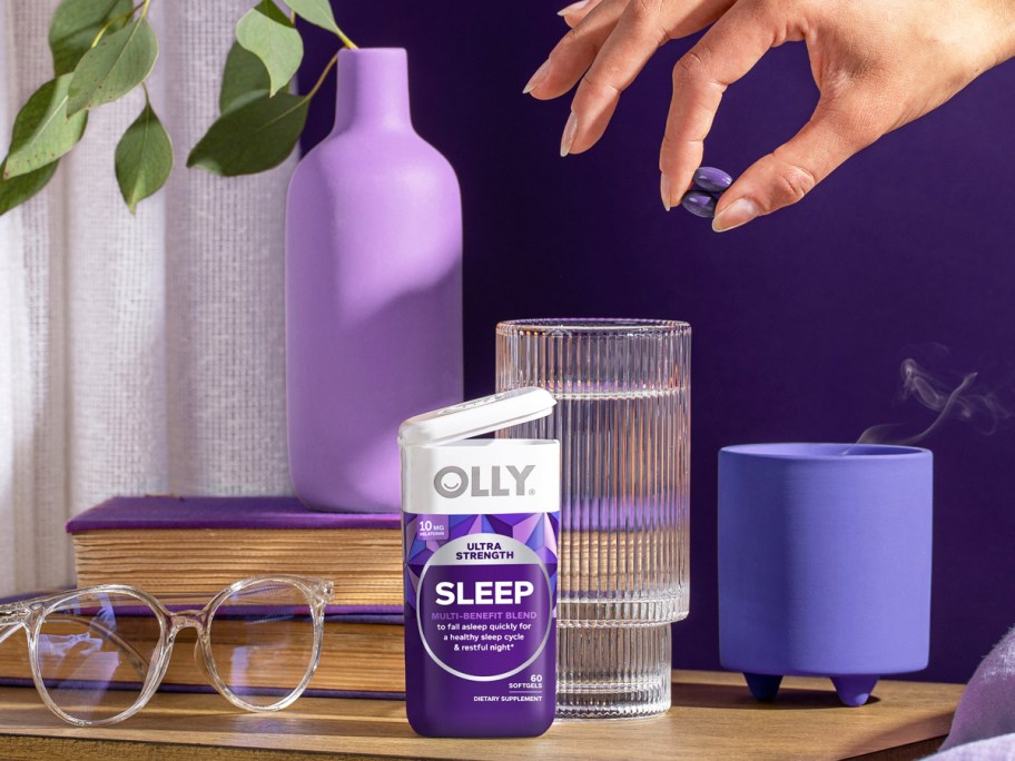 hand grabbing 2 purple OLLY Ultra Strength Sleep Softgels from bottle on nightstand