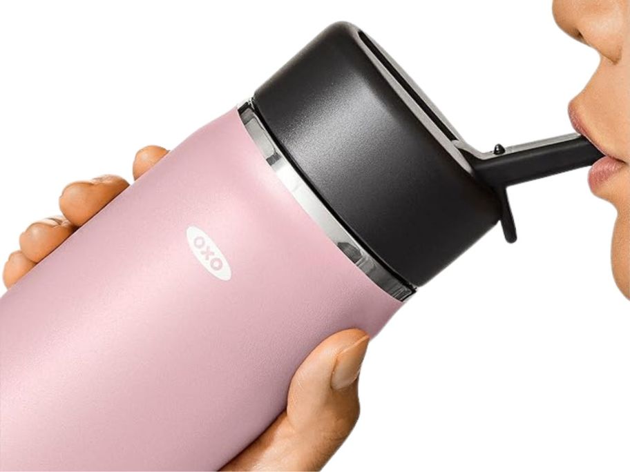A person drinking from an OXO Strive Water Bottle in pink 