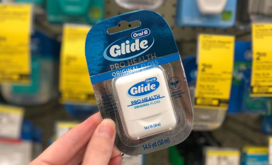 a womans hand holding a pack of oral b glide floss