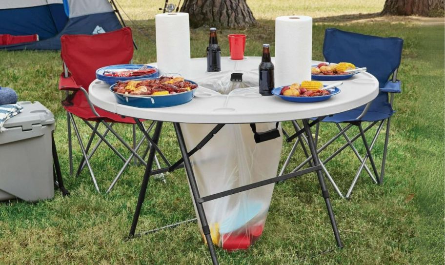 a white round camping table set with food and paper towels.