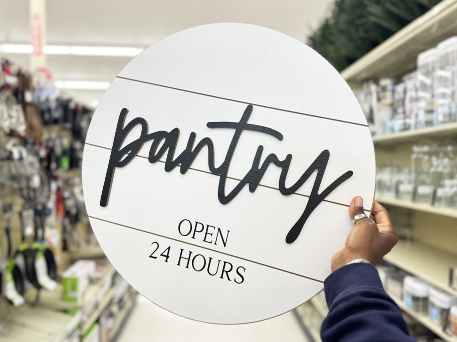 hand holding round white wood sign that says "pantry" on it