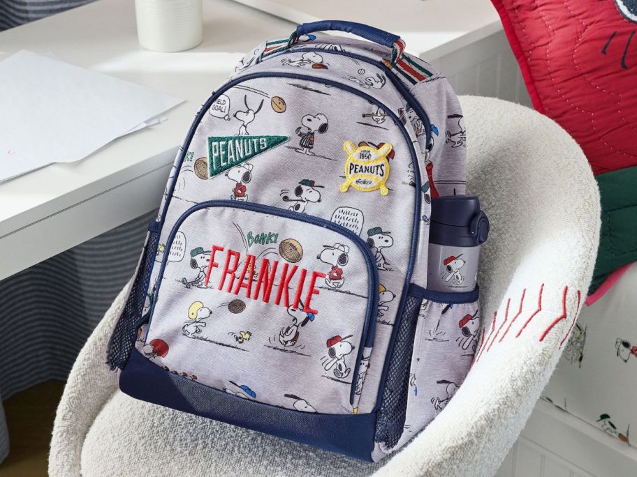 A small Mackenzie Peanuts Snoopy Sports Backpack on a Chair