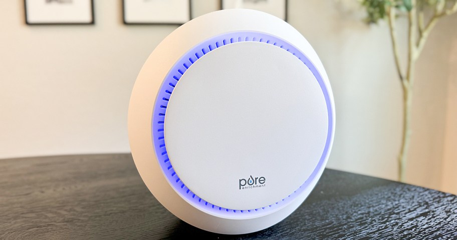 round white air purifier with blue light on black table