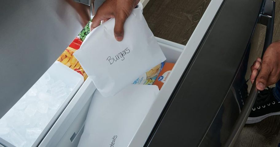 A person putting a wrapped parcel of meat in a freezer