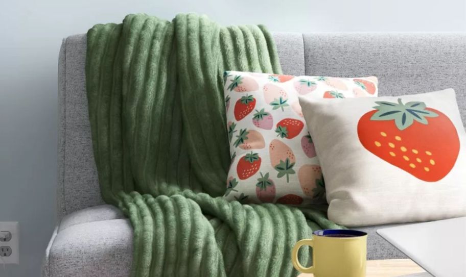 strawberry printed pillow 2 pack on a sofa with a green throw blanket