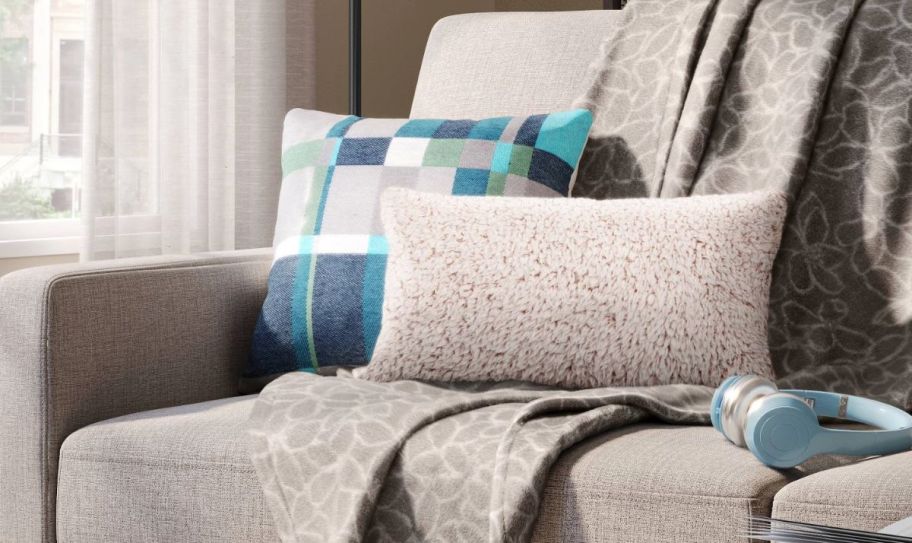 a blue teal and gray Plaid Throw Pillow shown with a shown with a faux fur lumbar pillow on a sofa 