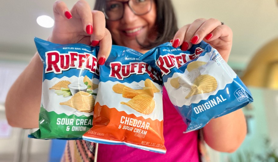 woman holding three bags of Ruffles chips