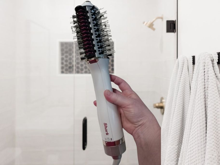 Shark SmoothStyle Heated Comb & Blow Dryer brush being held by hand in bathroom