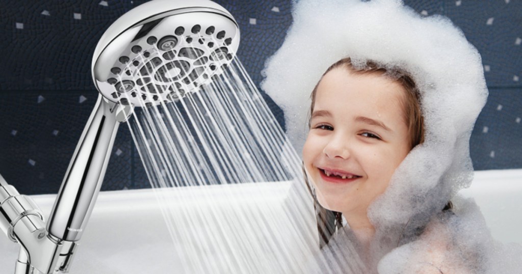 shower head spraying water onto little girl in bathtub