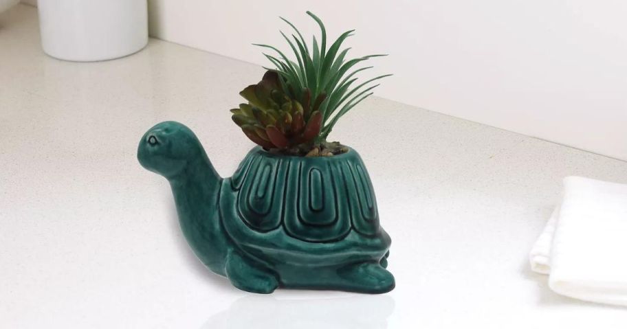 A teal turtle planted with faux greenery