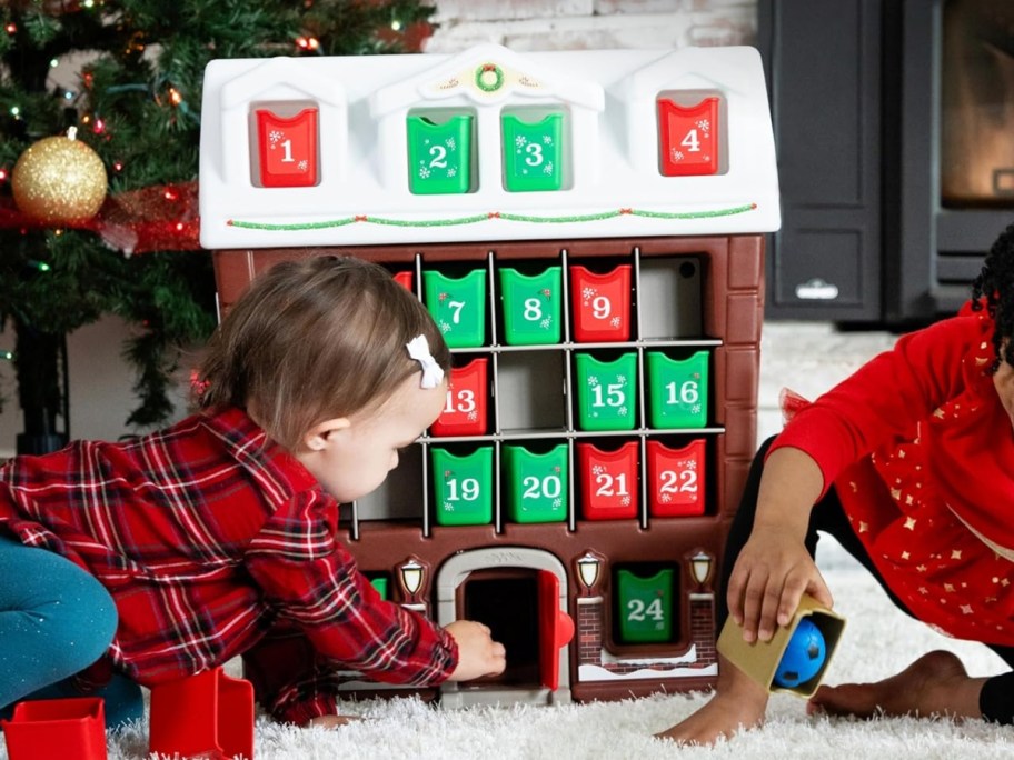 little girls playing with a large kid's advent calendar shaped like a house
