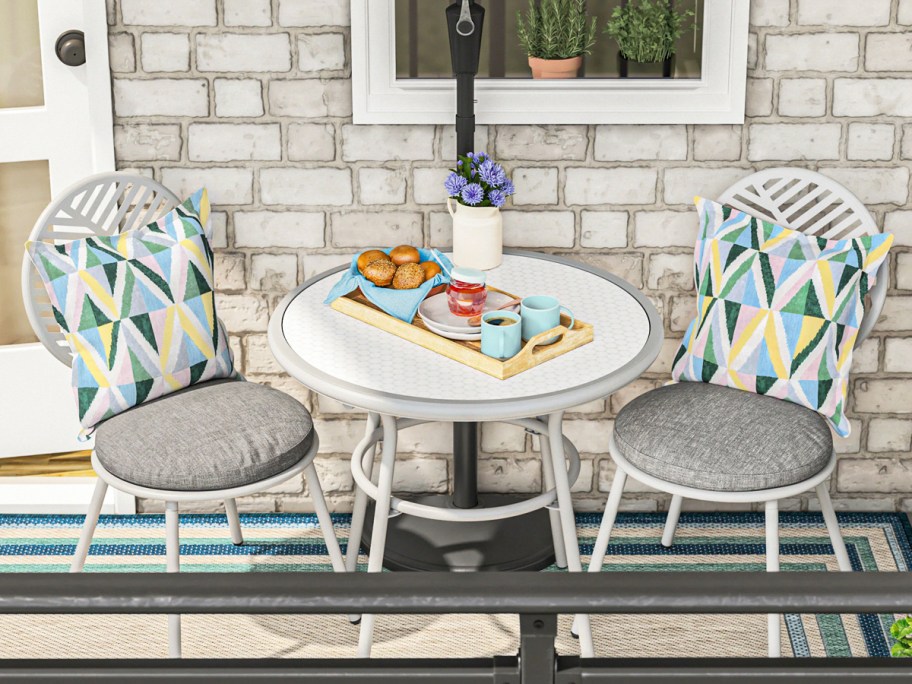 two white patio chairs with grey cushions and matching white table on balcony