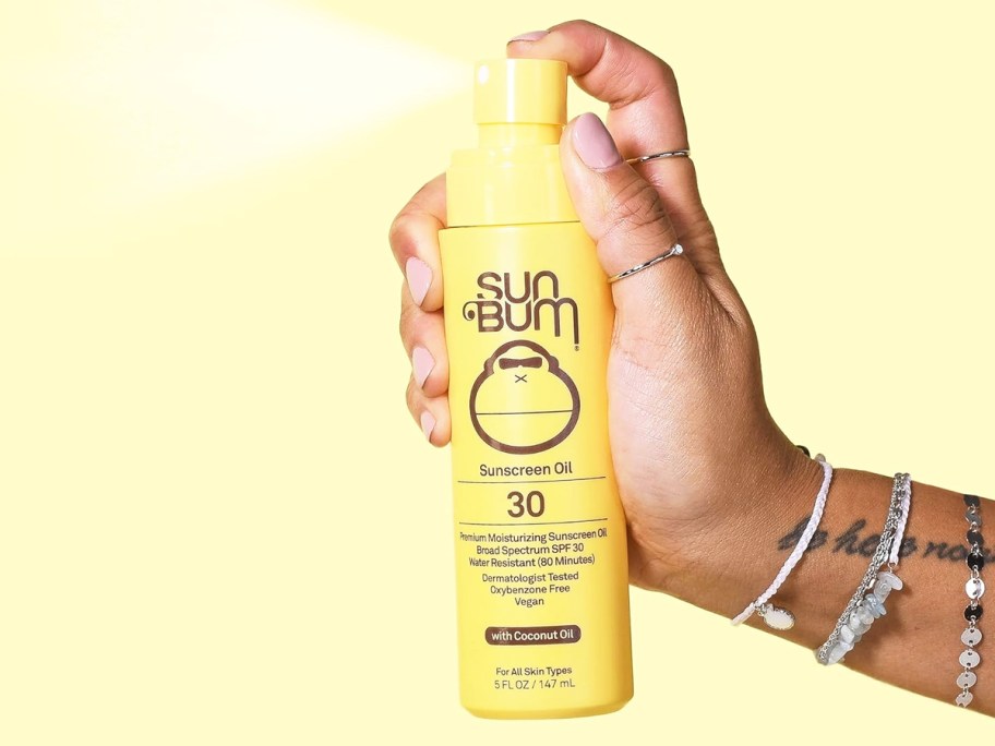 hand squirting a bottle of Sun Bum Original SPF 30 Sunscreen Oil