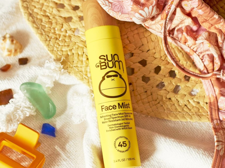 yellow bottle of Sun Bum Original SPF 45 Sunscreen Face Mist on top of a sun hat