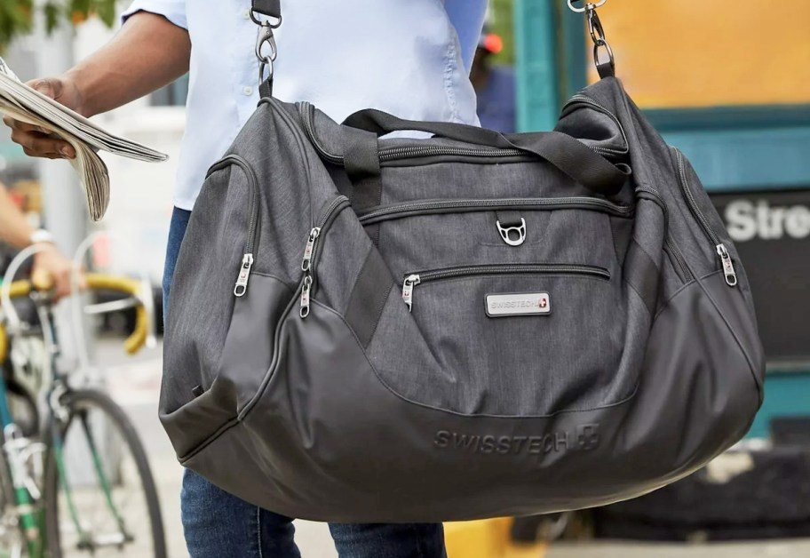 man carrying dark grey duffle bag