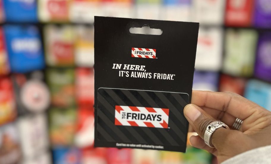 a womans hand holding a tgi fridays gift card in a store