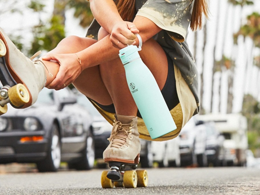 woman roller skating and holding teal water bottle